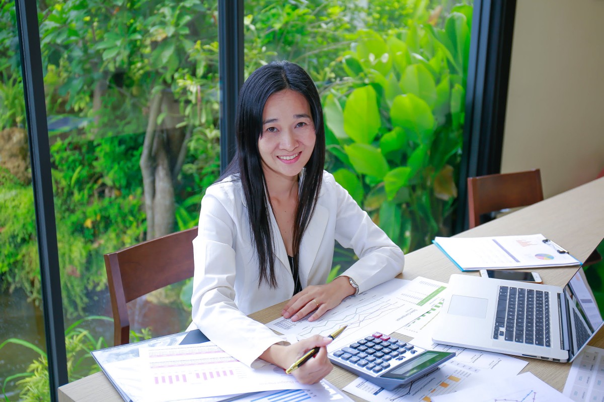 Smiling woman working with laptop and documents