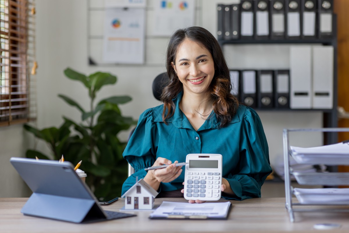 Smiling woman at office desk with calculator