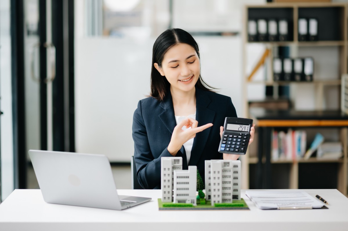 Businesswoman with calculator and model buildings.
