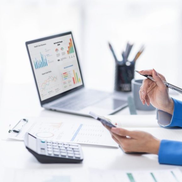 Professional analyzing financial data on laptop and documents.