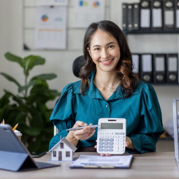 Smiling woman at office desk with calculator